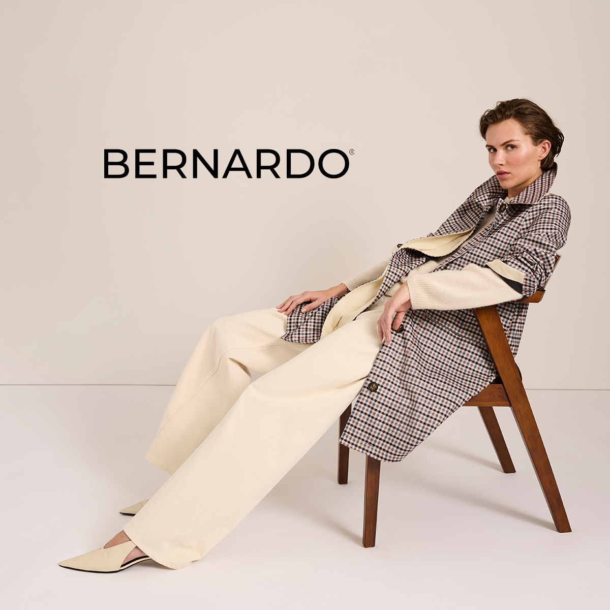 A model seated wearing a fashion outfit against a neutral background