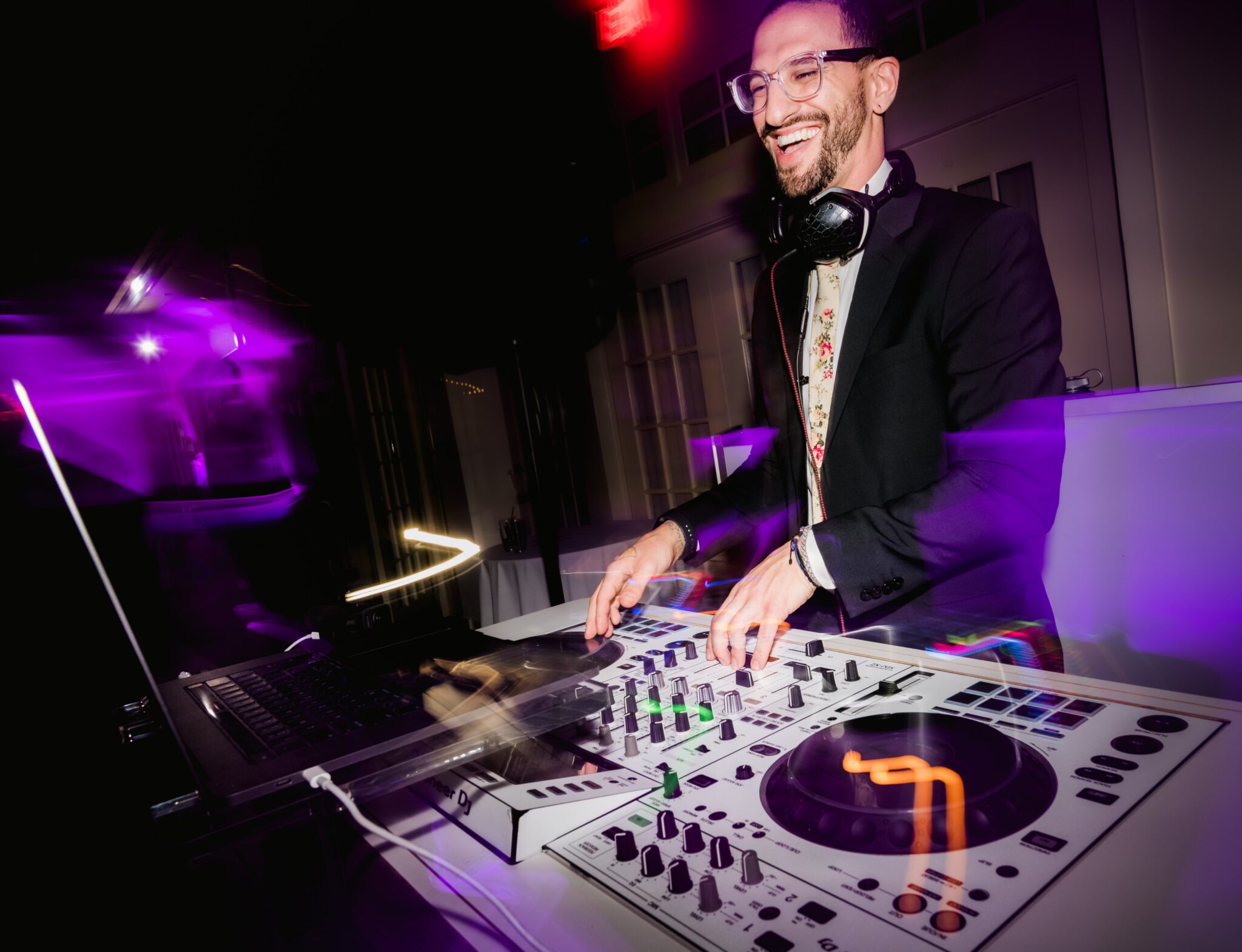 A DJ performing at a lively venue with colorful stage lighting
