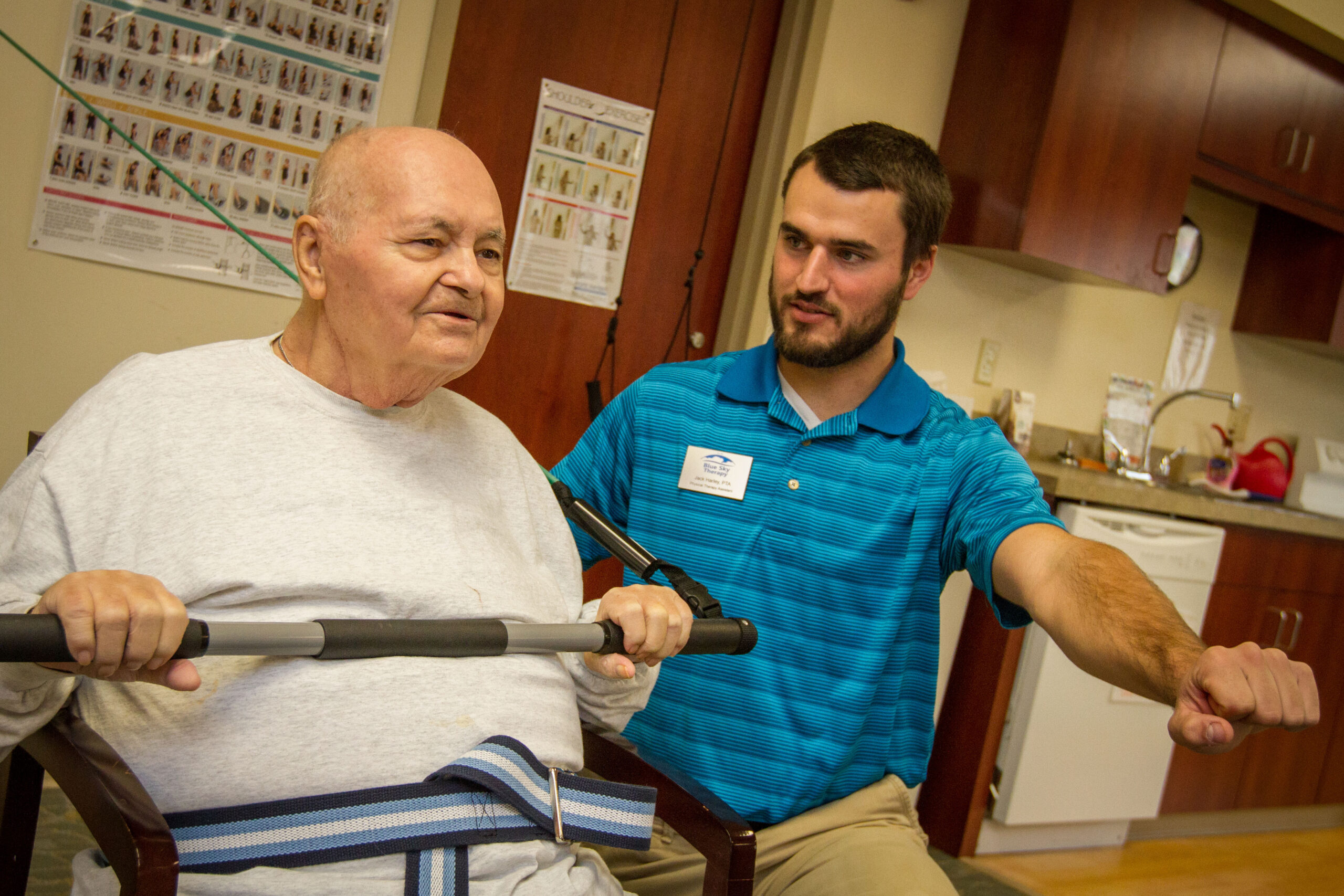 A senior man doing physical therapy exercises with a staff member