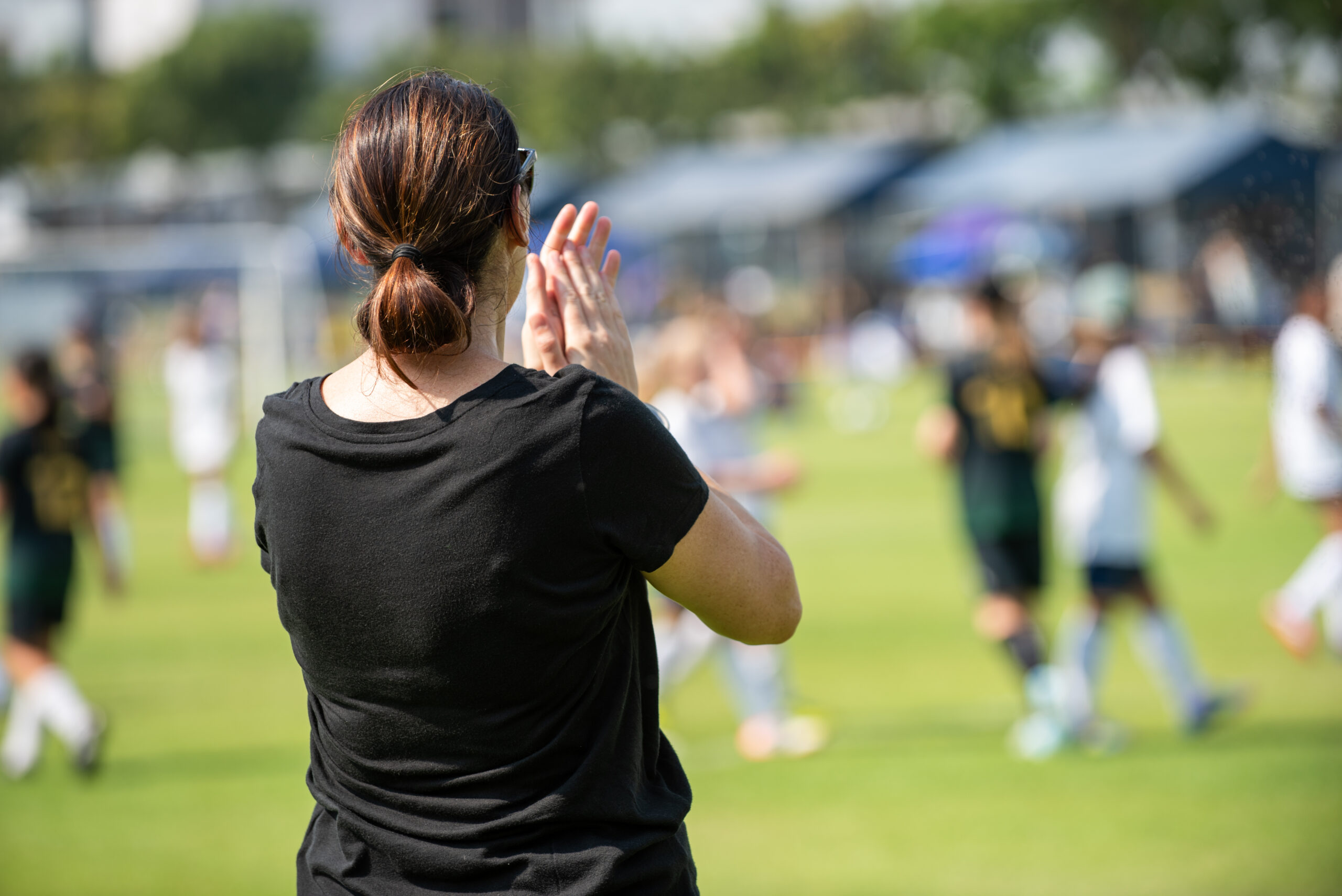 A parent watching a youth soccer game from the sideline