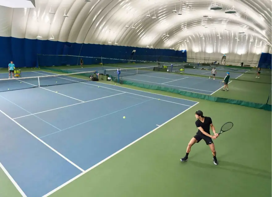 An indoor tennis facility with players on multiple courts